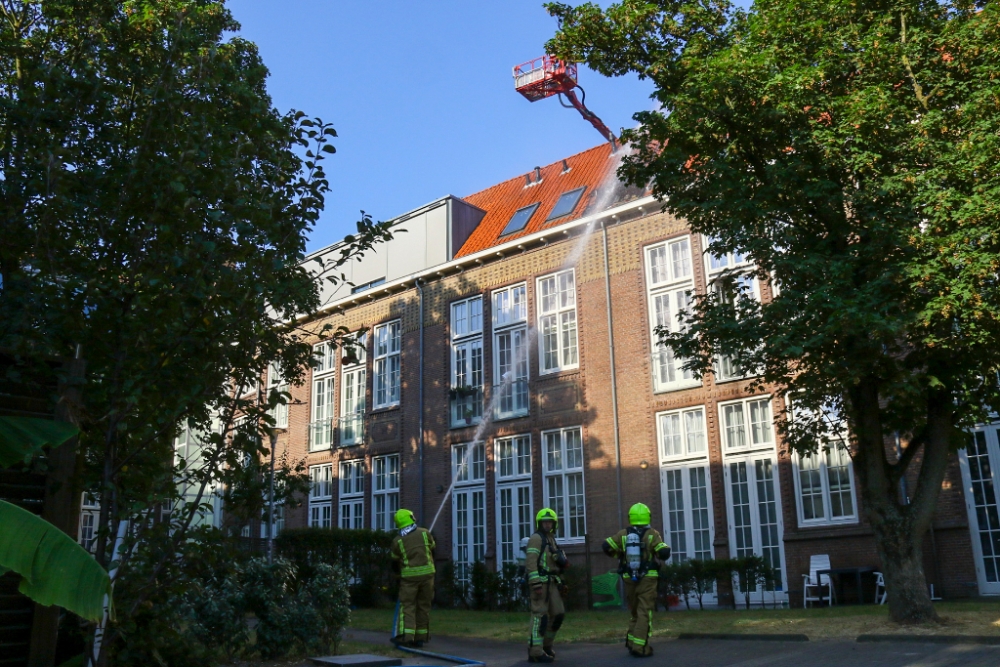 Brand in dak zorginstelling Vlaardingen, brandweer met stormram naar binnen