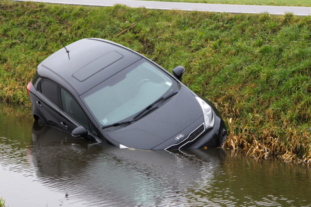 Auto glijdt in het water op Kandelaarweg