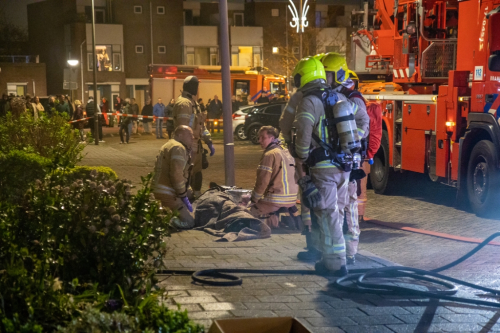 Man wordt door brandweer uit woning vol rook gesleurd