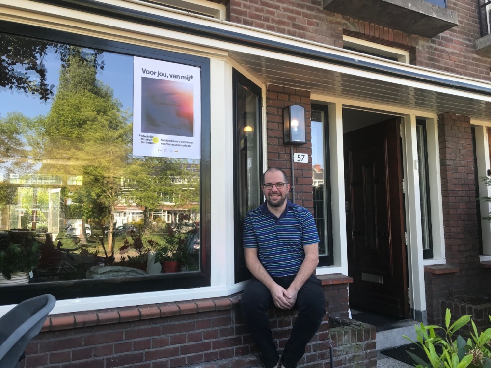 Cultuurwethouder Duncan Ruseler hangt eerste exemplaar Troostkunst uit Schiedam voor het raam